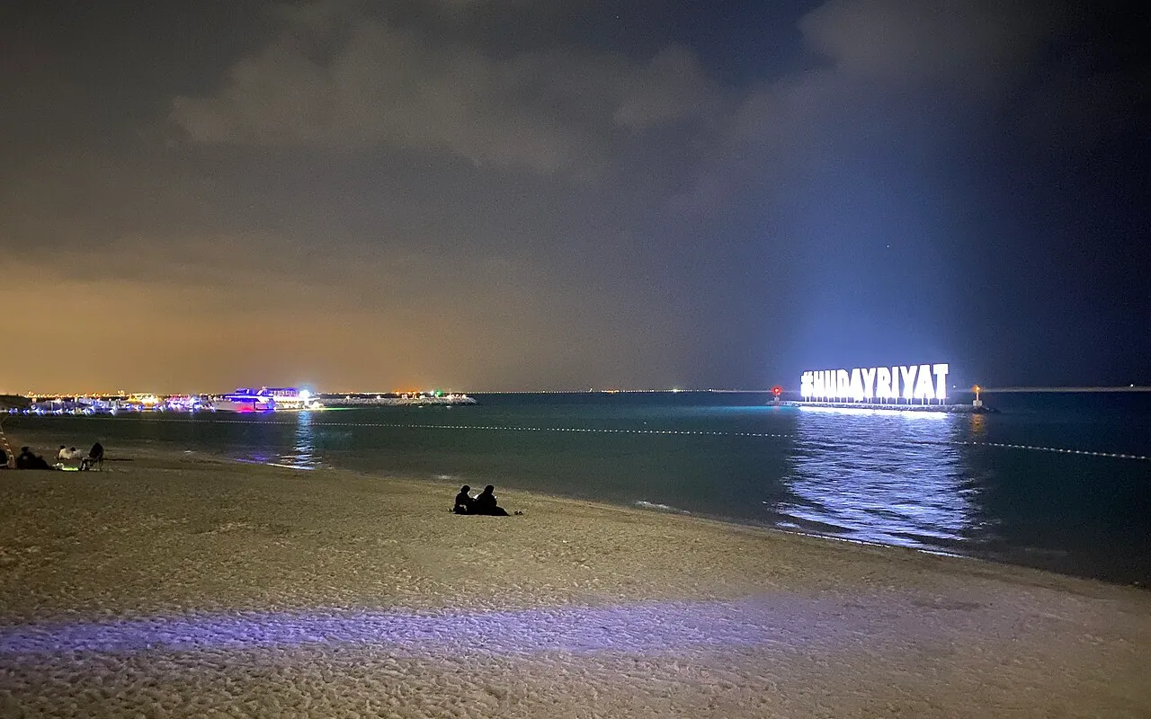 Hudayriyat Island beach and illuminated sign at night